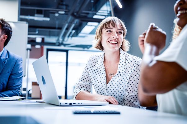 Kollegen in Businesskleidung lächeln während der Diskussion bei einem Treffen im Büro