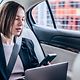 Eine Geschäftsfrau sitzt im Auto und hält eine Microsoft Teams Konferenz