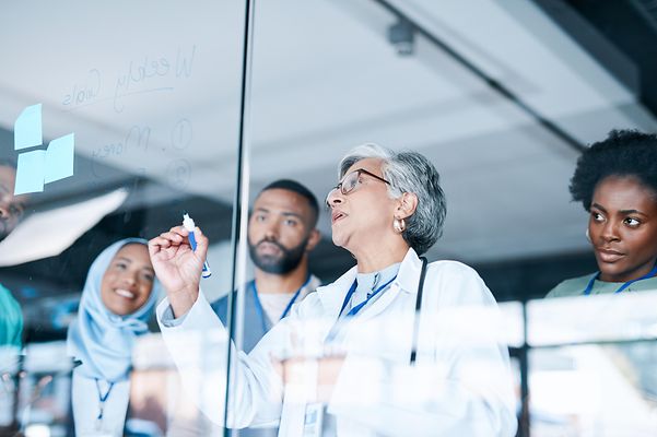 Mehrere Ärzte stehen in einem Krankenehaus vor einem Planungs Board und nutzten die Telematik Lösung