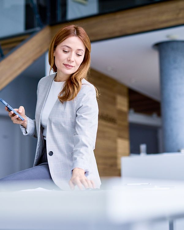 Geschäftsfrau, die Smartphone nutzt und in einem modernen Büro arbeitet.