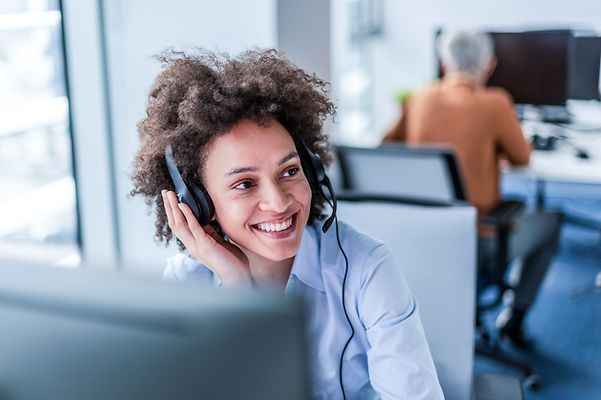Eine junge Frau spricht freundlich mit einem Kunden am Telefon