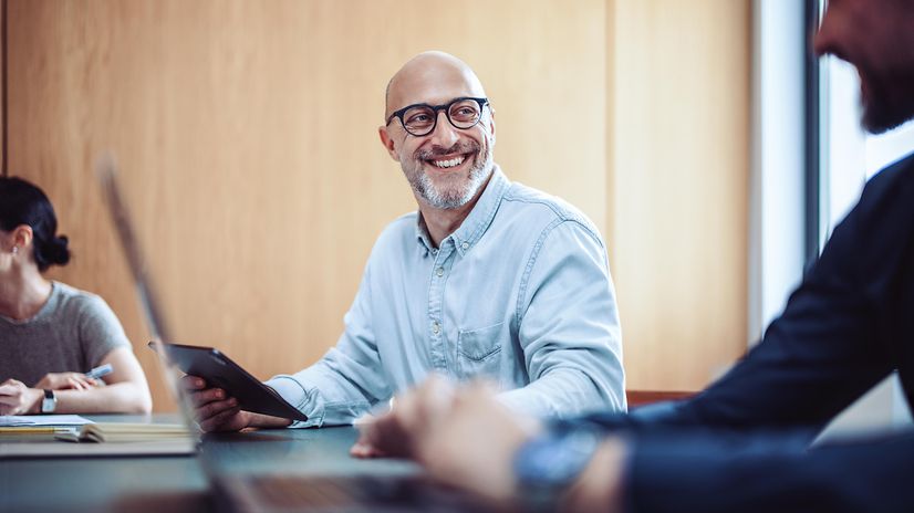 Lächelnder Mann mit Brille nutzt Phone für Microsoft Teams X