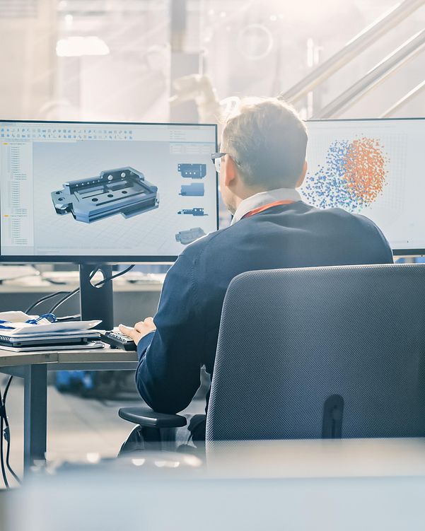Ein Mann arbeitet am Rechner mit zwei Monitoren