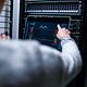 Blick über die Schulter eines Mannes, der eine Analyse an einem Server durchführt. 