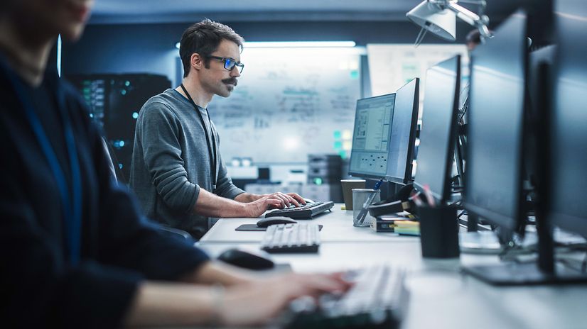 Ein Security Spezialist arbeitet an einem Desktop-Computer und überwacht IT-Systeme mittels Cyber Defense Lösungen