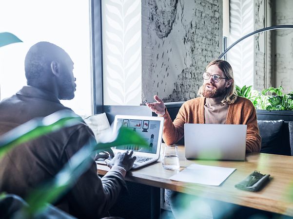 Kollegen sitzen im Büro und diskutieren über Zoom X Rooms
