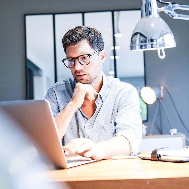 Mann arbeitet am Laptop im Büro und nutzt Microsoft Copilot