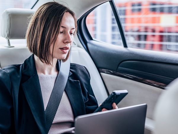 Frau im Auto sucht in Contacts nach einem Business Konktakt für einen Anruf.