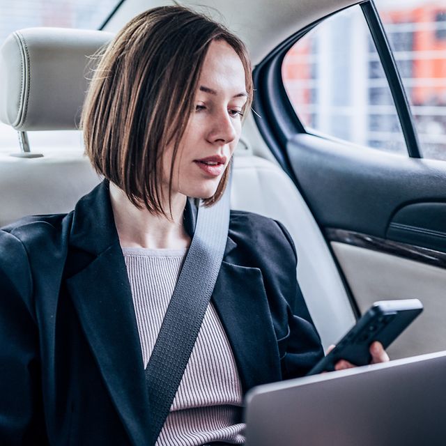 Frau im Auto sucht in Contacts nach einem Business Konktakt für einen Anruf.