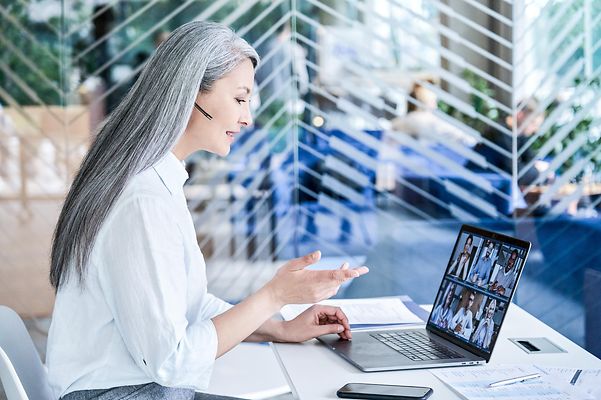 Eine Frau telefoniert vorm Laptop und nutzt dabei CompanyFlex.
