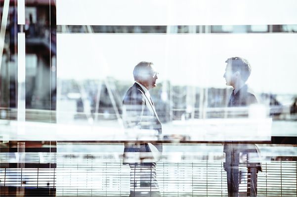 Zwei Männer im Anzug unterhalten sich am Flughafen zur FreeMove Allianz.