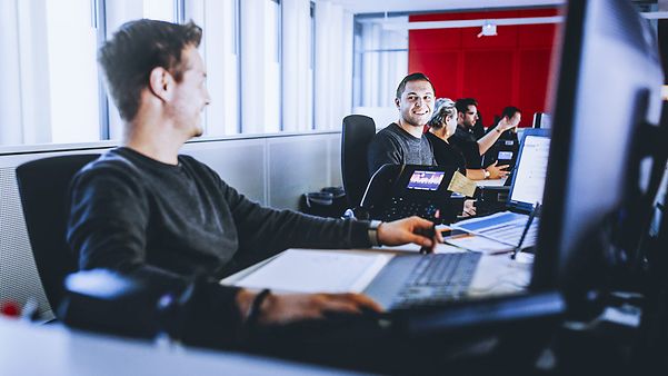 Mehrere Personen sitzen nebeneinander und schauen auf ihre Bildschirme.