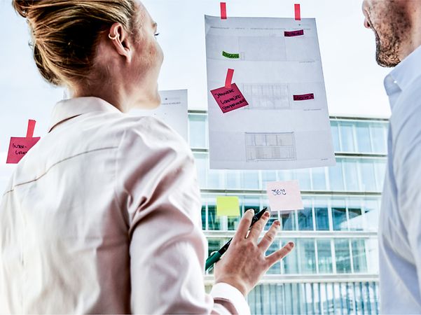 Eine Frau und ein Mann schauen auf ein Blatt Papier.