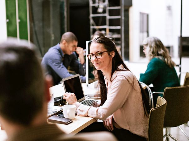 Ein Frau im Großraumbüro unterhält sich mit einem Kollegen über Managed IT-Services