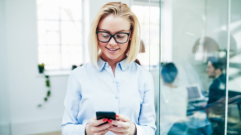 Frau liest auf Ihrem Smartphone eine SMS und lächelt
