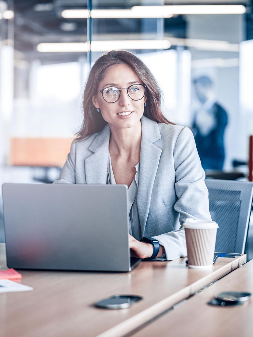 Eine Frau schaut im modernen Büro am Laptop das Webinar: Private TelekomCLOUD