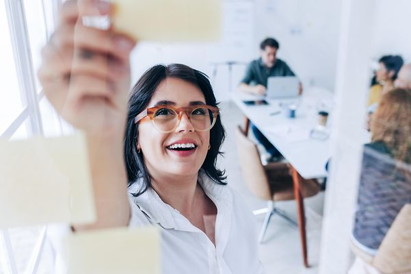 Frau im Meeting erläutert Kollegen die Vorteile von LANCOM Cloud Self Service für das Netzwerkmanagement.