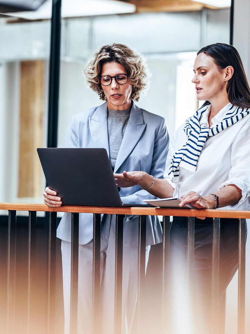Zwei Frauen im Gespräch an einem Laptop an einem mobilen Arbeitsplatz außerhalb des Büros