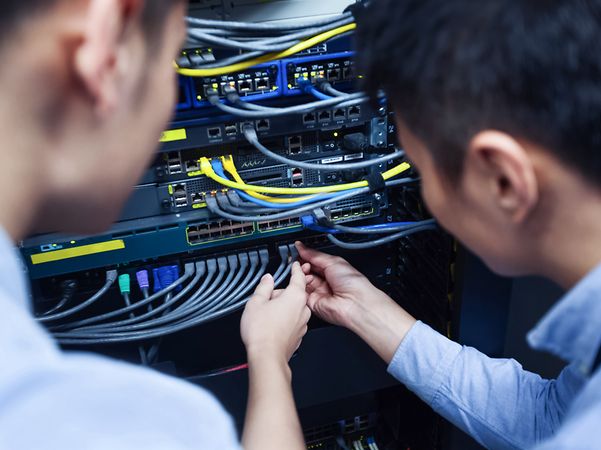 Zwei Techniker prüfen Kabel an einem Rechenschrank