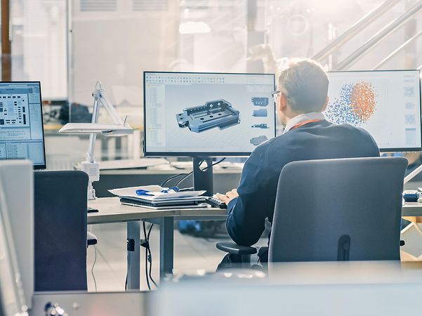 Ein Mann arbeitet in einem Büro am Rechner mit zwei Monitoren