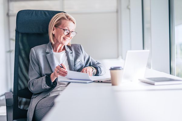 Ältere Geschäftsfrau arbeitet am Laptop in einem modernen Büro