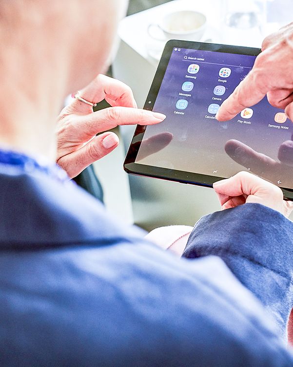 Zwei Kollegen betrachten Cloud- und Infrastruktur Lösungen auf einem Tablet.