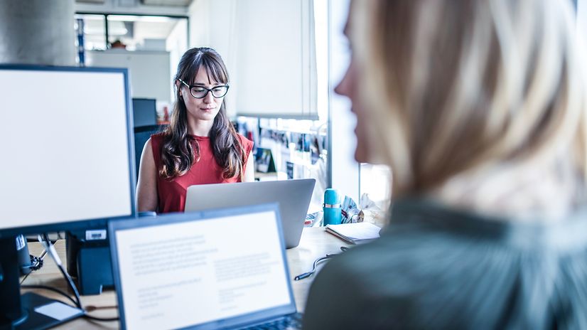 Zwei Frauen arbeiten in einem Büro digital zusammen.
