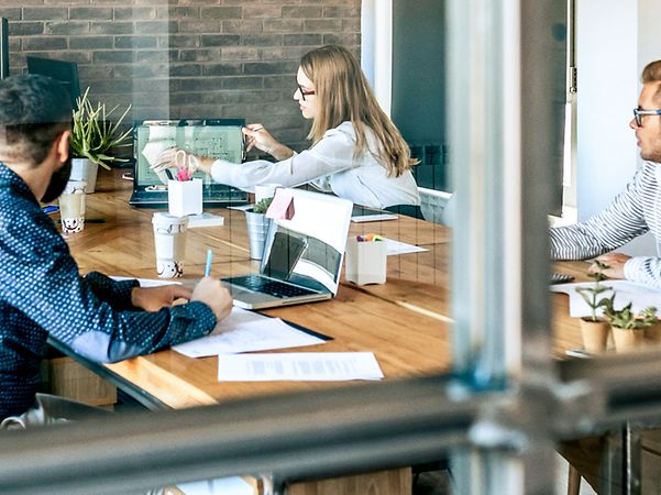 Mehrere Kollegen sitzen an einem großen Besprechungstisch und diskutieren über die MagentaBusiness Cloud.