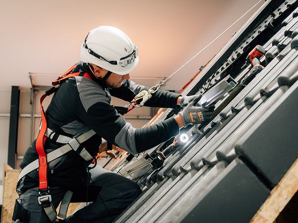 Enpal Mitarbeiter mit Helm und Schutz installiert Solaranlage auf dem Dach