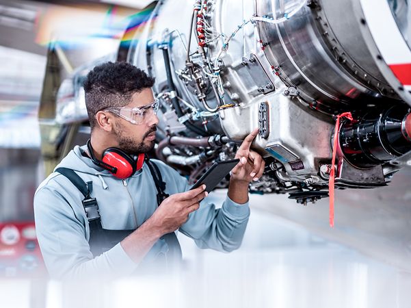 Flugzeugwartungsmechaniker, der Daten vor dem Düsentriebwerk überprüft