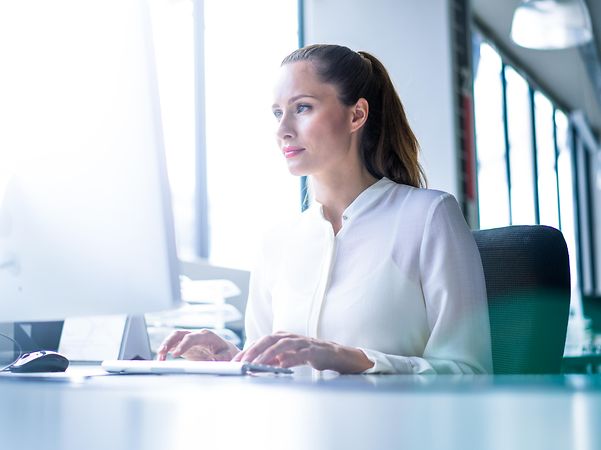 Geschäftsfrau überzeugt sich von den Vorteilen von CompanyFlex SIP-Trunk am PC.