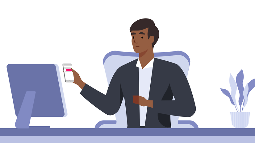 Mann am Schreibtisch mit Smartphone in der Hand mit Blick auf den Monitor