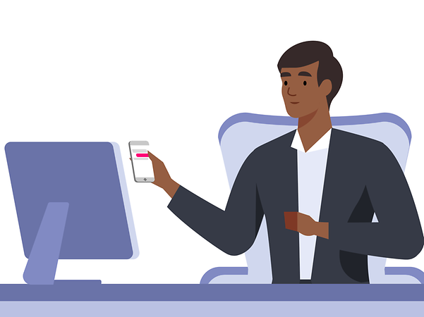 Mann am Schreibtisch mit Smartphone in der Hand mit Blick auf den Monitor