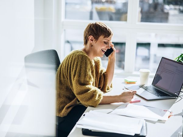 Lächelnde Geschäftsfrau nutzt den Company DSL Tarif mit Doppelflat von T Business.