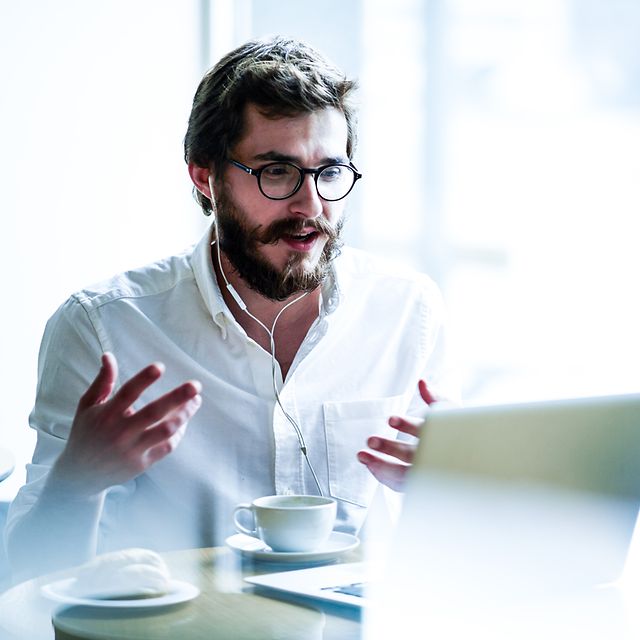 Business Analytics Mann sitzt hinter seinem Laptop in eine digitalen Konferenz