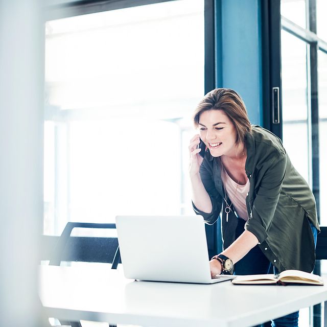 Geschäftskundin telefoniert und arbeitet am Laptop im Büro – nutzt Kombiangebot von Telekom