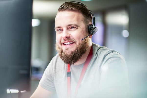 Servicemitarbeiter telefoniert über Headset und lächelt 