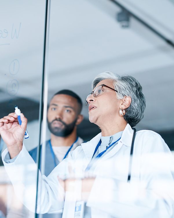 Mehrere Ärzte stehen in einem Krankenehaus vor einem Planungs Board, was über 5G Campus-Netze vernetzt ist