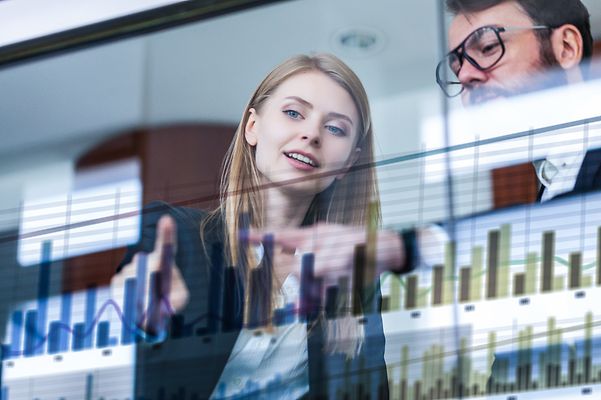 Zwei Geschäftsleute vor futuristischem Display analysieren Daten