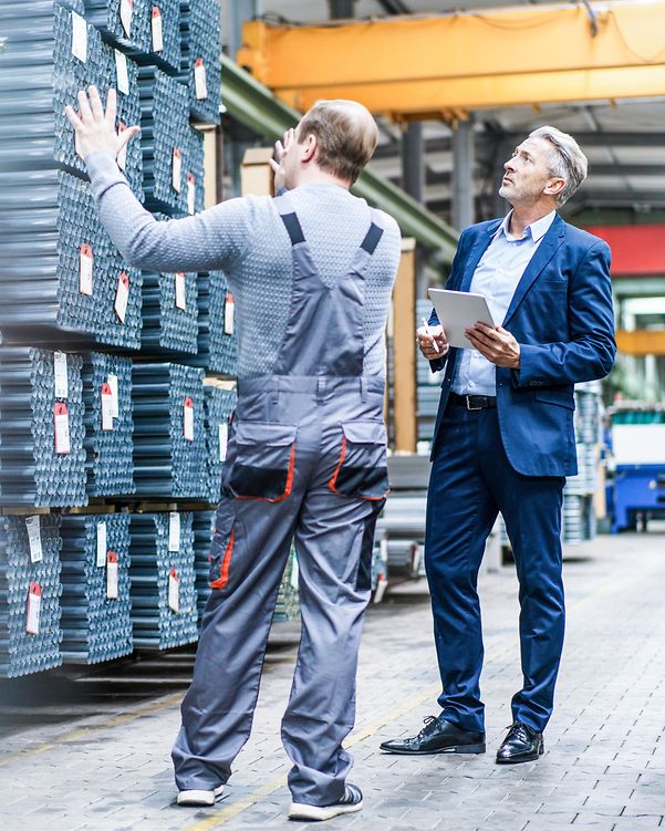 Mitarbeiter in Produktionshalle im Gespräch über Planung und Optimierung – Ausdruck von T Business Gestaltungswille