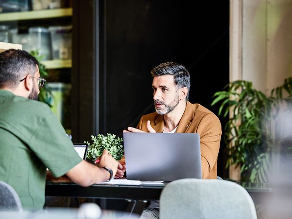Zwei Kollegen im Gespräch am Laptop Einblick in die Unternehmenskultur von T Business