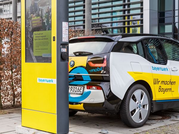 blau weiss gelbes Elektrofahrzeug an gelber Ladesäule von Bayernwerk
