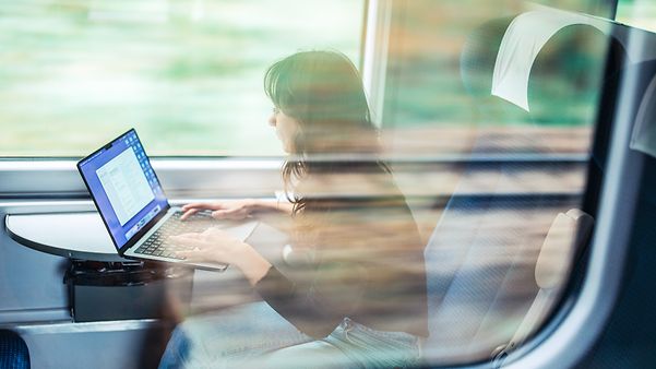 Im Zug arbeitet eine Frau konzentriert an ihrem Laptop – trotz wechselnder Netzverbindung bleibt alles stabil.