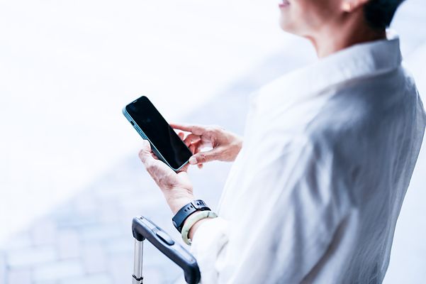 Ein Geschäftsreisender nutzt sein Smartphone unterwegs – mit Mobile Optimization Pro bleibt die Verbindung sicher.