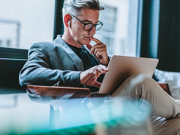 Geschäftsmann vertieft sich in digitale Fachinhalte am Laptop – Know-how & Insights von T Business