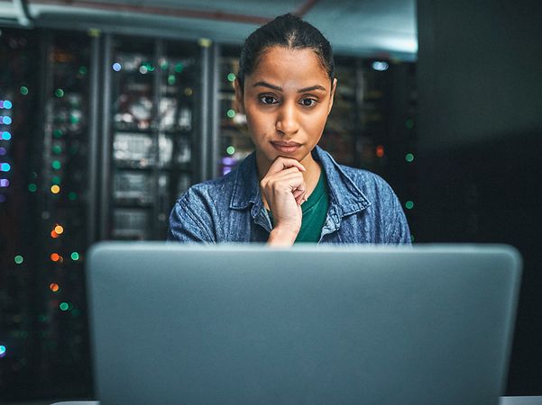 Security-Spezialistin arbeitet im Serverraum am Laptop