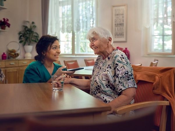 Pflegerin übersetzt simultan über ihr Smartphone für eine ältere Frau