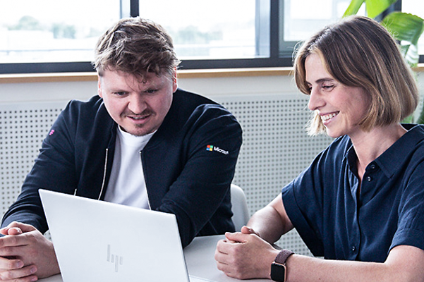 Berater sitzt mit einer Kundin zusammen und berät Sie zu Microsoft Teams Telefonie von der Telekom