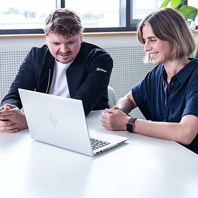 Berater sitzt mit einer Kundin zusammen und berät Sie zu Microsoft Teams Telefonie von der Telekom