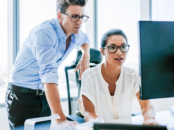 Zwei Personen schauen auf einen Computerbildschirm